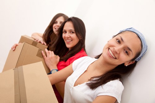 Professional movers carrying furniture through a Southfields residential street