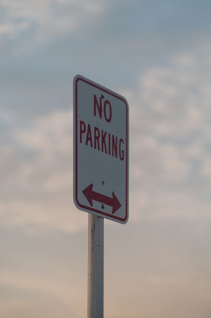 A close-up image of a rectangular metal sign mounted on a textured black surface, indicating 'PRIVATE PROPERTY LOADING ZONE ONLY' in bold black letters on a white background. The sign appears slightly